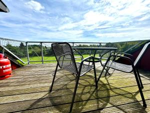 a pair of chairs sitting on a wooden deck at Hof Vierzehnender im Hohen Venn - 70qm Fachwerk-Studio - grosses Wohn-Schlafzimmer mit Dachterrasse und Kaminofen - separate Küche - perfekt für Paare - Monschau - Eifel - Hunde willkommen - Islandpferde in Monschau