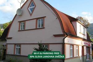 a building with a pitched roof with a sign in front at Apartmány Holiday Pec in Pec pod Sněžkou