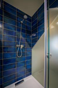 a bathroom with a shower with blue tiles at Bográcsozó Vendégház in Békésszentandrás