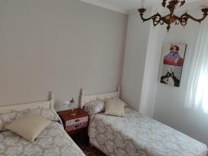 a bedroom with two beds and a table and a chandelier at Apartamento's Montiño in O Grove