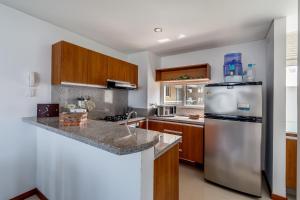 una cucina con frigorifero in acciaio inossidabile e mobili in legno di Apartamento - Condominio Zazué a Santa Marta