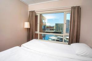 a bedroom with a bed and a large window at Home Hotel Bryggeparken in Skien