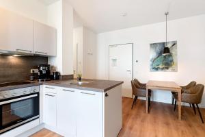 Una cocina con gabinetes blancos y una mesa de madera. en Km Style Apartments 6, en Freiburg im Breisgau