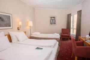 a hotel room with two beds and a chair at Home Hotel Bryggeparken in Skien