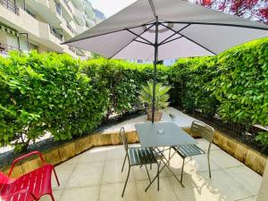a table and chairs with an umbrella on a patio at Studio chic piscine, jardin et parking, Lyon 3 in Lyon