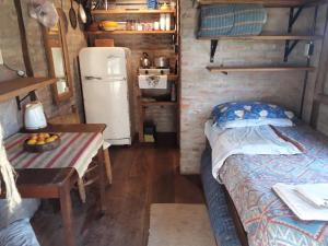 Una pequeña habitación con una cama y una nevera. en El ranchito, en Santa Coloma