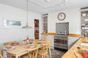 a kitchen with a table with chairs and a clock on the wall at The Old Shop House in Galmpton-on-the-Dart