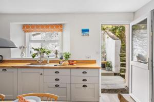 a kitchen with white cabinets and a window at The Old Shop House in Galmpton-on-the-Dart +37 photos