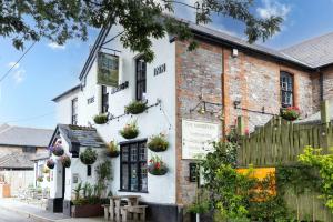 a white building with potted plants on it at The Old Shop House in Galmpton-on-the-Dart