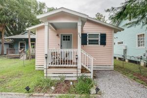 uma pequena casa cor-de-rosa com um alpendre em The Swamp Rose Cottage em Bay Saint Louis