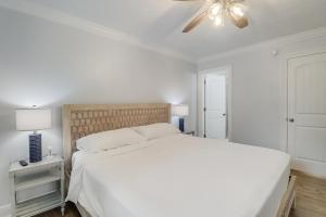 um quarto branco com uma cama e uma ventoinha de tecto em The Swamp Rose Cottage em Bay Saint Louis