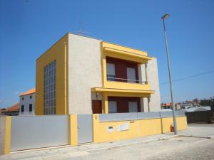 un edificio blanco y amarillo con una valla delante en Casas Solar da Torre en Navais