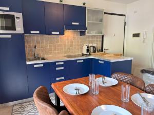 巴德小基希海姆REHKITZ Apartment的厨房配有蓝色橱柜和一张带椅子的木桌