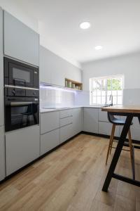 a kitchen with white cabinets and a wooden table at Luxuosa Villa com Piscina, Garagem e Vista Mar in Tavira