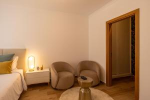 a bedroom with two chairs and a bed and a mirror at Luxuosa Villa com Piscina, Garagem e Vista Mar in Tavira