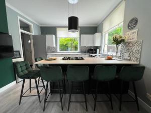 una cocina con una isla con taburetes de bar verde en Loch Lomond Mews, en Balloch