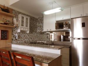 uma cozinha com armários brancos e um frigorífico de aço inoxidável em Porto Real Apartment Angra em Mangaratiba
