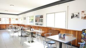 a restaurant with tables and chairs and windows at Pensión Albergue Gonzar in Portomarin
