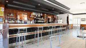 a bar in a restaurant with stools at Pensión Albergue Gonzar in Portomarin +22 photos