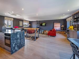 a kitchen and living room with a red couch at Farmyard House in Amlwch