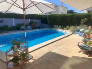 a swimming pool with an umbrella and a table with at MAR VERDE - Parede-Cascais in Parede