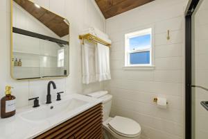a bathroom with a sink and a toilet and a mirror at Vista Verde Farm Retreat - Stylish Cabins Nearby Springs in Ellisville