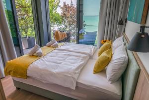 a bedroom with a bed with pillows and a large window at BJ81 Suite Hotel in Siófok +88 photos