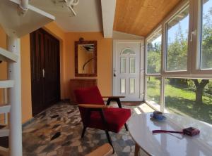a living room with a table and a red chair at Kućica Osmeha in Donja Ralja