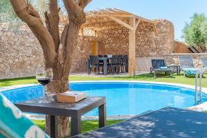 シャーラにあるVilla Oliva 4 bedroom villaのプールサイドのテーブルに座ってワインを楽しめます。