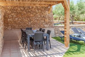 シャーラにあるVilla Oliva 4 bedroom villaの石壁のパティオ(テーブル、椅子付)
