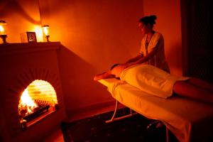 a woman sitting on a bed in front of a fire place at Riad Shama Suites & Spa in Marrakesh