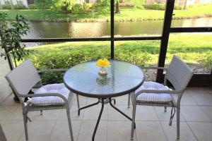 a glass table with two chairs and a vase with a yellow flower at Florida Bella Rosa near IMG Academy & beaches in Bradenton