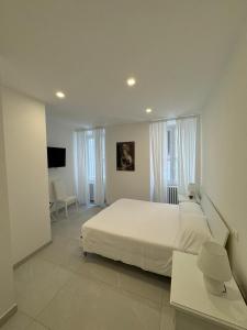 a white bedroom with a large bed and a tv at Re House Suite & Deluxe Apartament in Ascoli Piceno