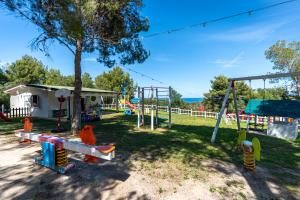 a playground with a tree and colorful swings at Mangia's Pollina Resort in Cefal&ugrave;