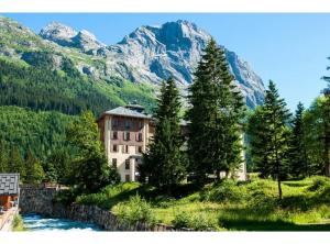 a building on a hill with a river and mountains at La Bévéria in Pralognan-la-Vanoise