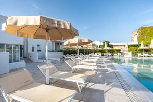 a row of chairs and umbrellas next to a pool at Mangia's Pollina Resort in Cefalù