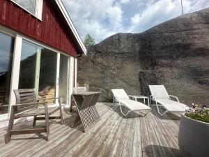 a wooden deck with chairs and a table and a mountain at Guest House in Tjøme