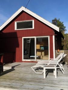 a red barn with a pair of chairs on a deck at Guest House in Tjøme
