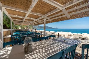 a table with blue chairs and the ocean in the background at Mangia's Pollina Resort in Cefalù