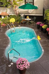 una piccola piscina con fiori e ombrellone di Crowne Pointe Historic Inn Adults Only a Provincetown