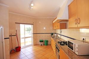 a kitchen with a stove and a microwave at Casas do SOL GuestHouse Lagos in Lagos +11 photos