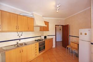 a kitchen with wooden cabinets and a white refrigerator at Casas do SOL GuestHouse Lagos in Lagos