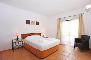 a bedroom with a bed and a chair and a window at Casas do SOL GuestHouse Lagos in Lagos