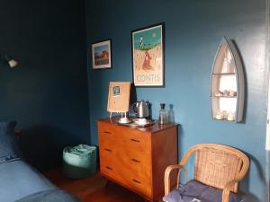 - une chambre avec une commode en bois et un mur bleu dans l'établissement Chez Solange et Paul, à Mézos