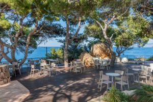 a restaurant with tables and chairs and the ocean at Mangia's Pollina Resort in Cefalù