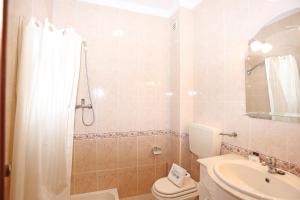a bathroom with a shower and a toilet and a sink at Casas do SOL GuestHouse Lagos in Lagos
