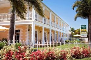 a building with a fence and palm trees and flowers at White Lace Motor Inn in Mackay