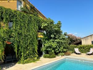 an ivy covered house with a swimming pool at La Cassiopée in Caromb