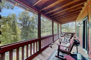 a screened porch with two rocking chairs and windows at Rustic Ridge Cabin in Young Harris