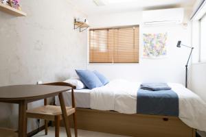 a bedroom with a bed and a table and a window at Kaku Studio Apartment Ikebukuro in Tokyo